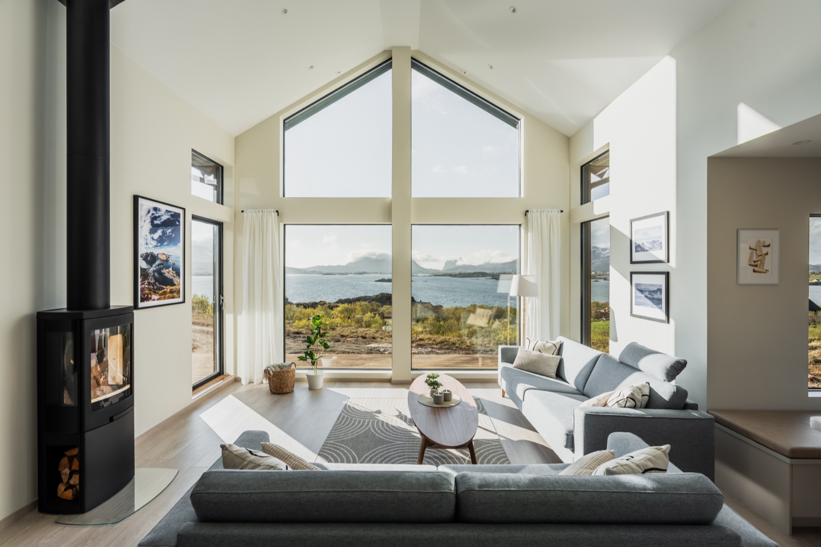 The view from Lofotendreams: sea and mountains through the cathedral windows, wood stove lit