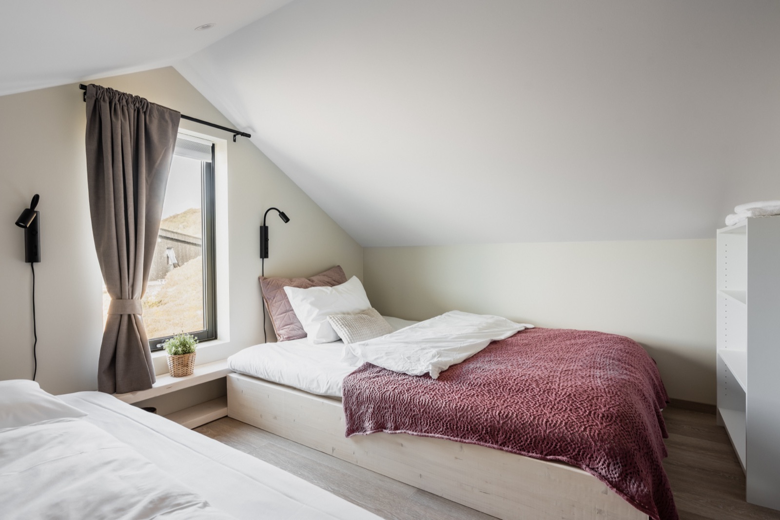 Loft bedroom with the bed facing a window onto the fjord and mountains