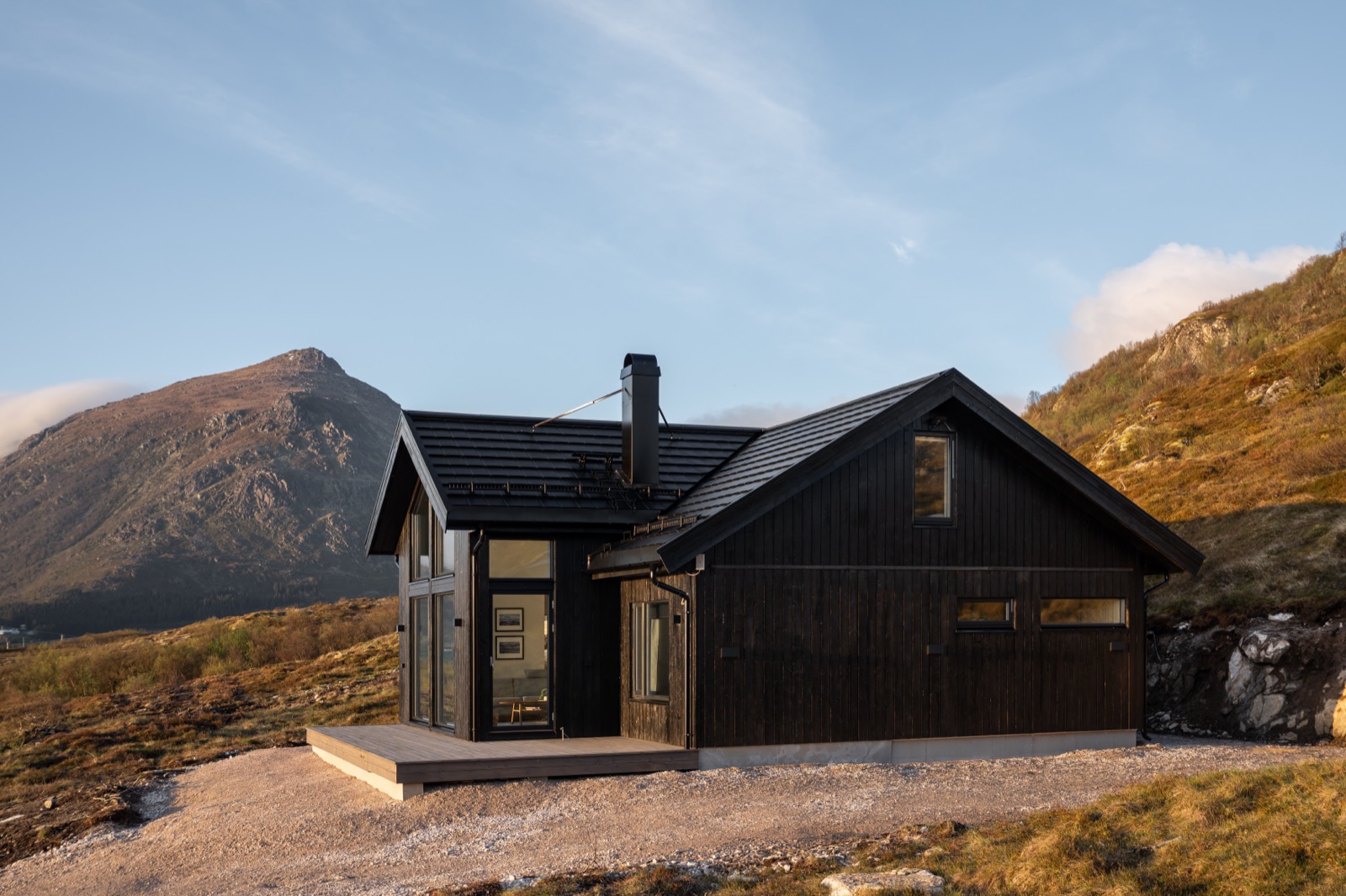 The black timber chalet in golden evening light with the mountain behind